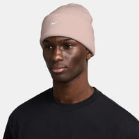 Person wearing a pink Nike beanie on a white background