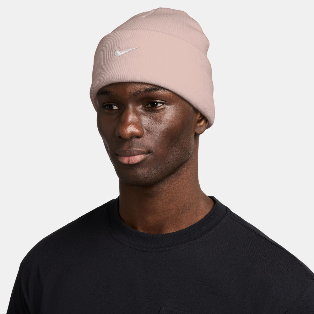 Person wearing a pink Nike beanie on a white background